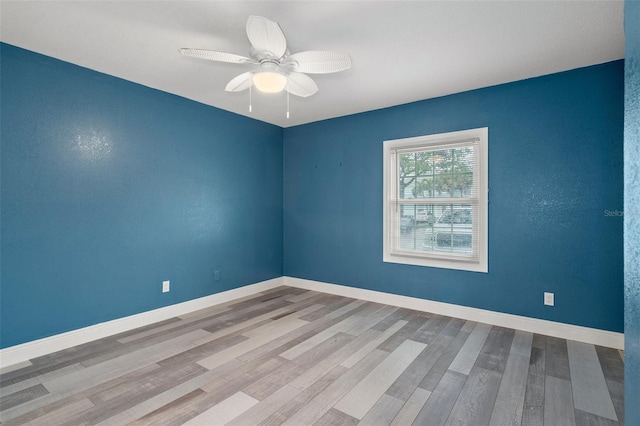 empty room with a ceiling fan, baseboards, and wood finished floors