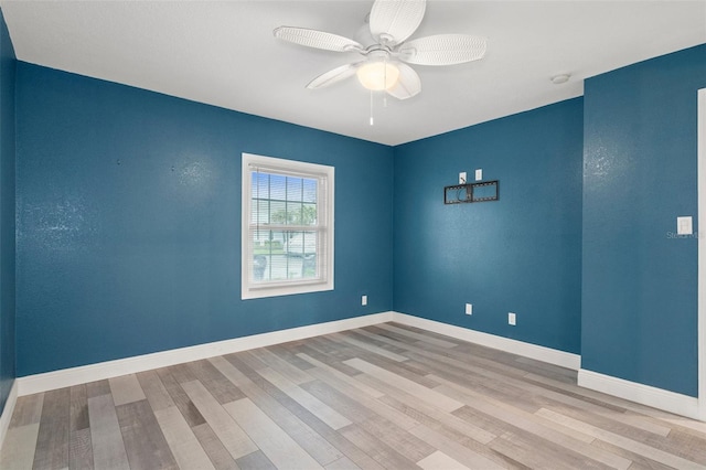 empty room with wood finished floors, a ceiling fan, and baseboards