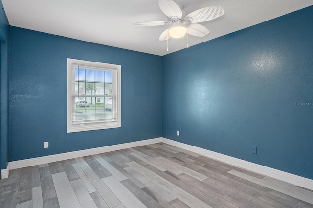 empty room featuring a ceiling fan, baseboards, and wood finished floors