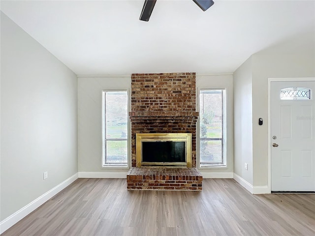 unfurnished living room with ceiling fan, a fireplace, baseboards, and wood finished floors