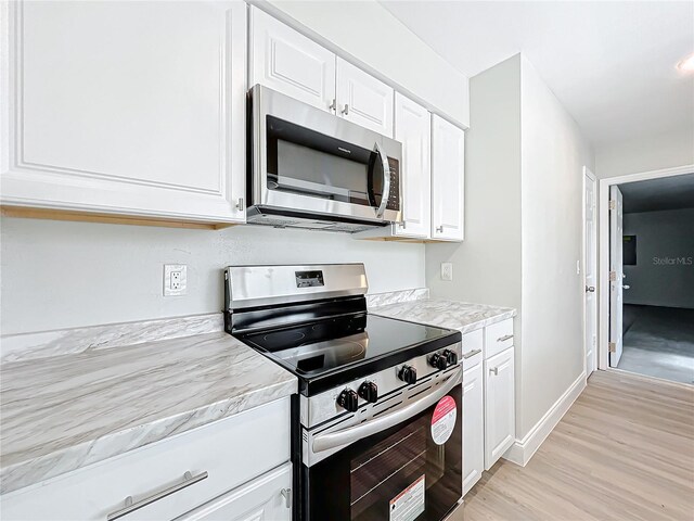 kitchen featuring white cabinets, light wood finished floors, appliances with stainless steel finishes, and light countertops