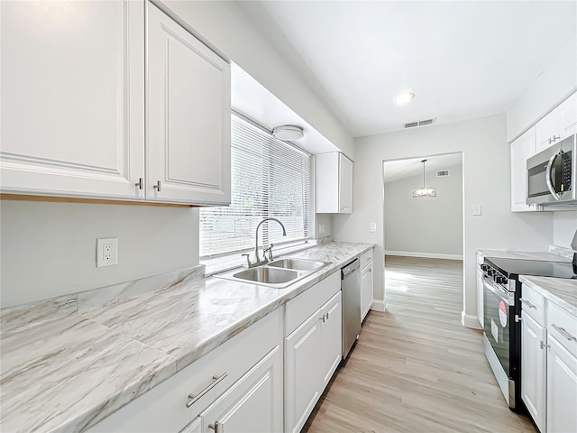 kitchen with a sink, visible vents, light wood-style floors, white cabinets, and appliances with stainless steel finishes