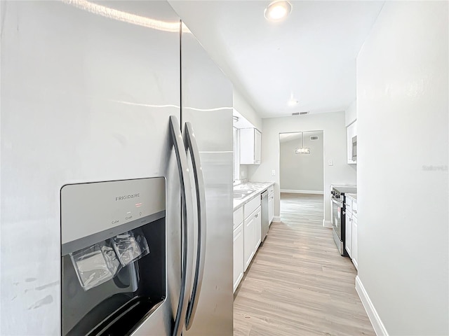 kitchen featuring stainless steel appliances, visible vents, light countertops, light wood-style flooring, and white cabinetry