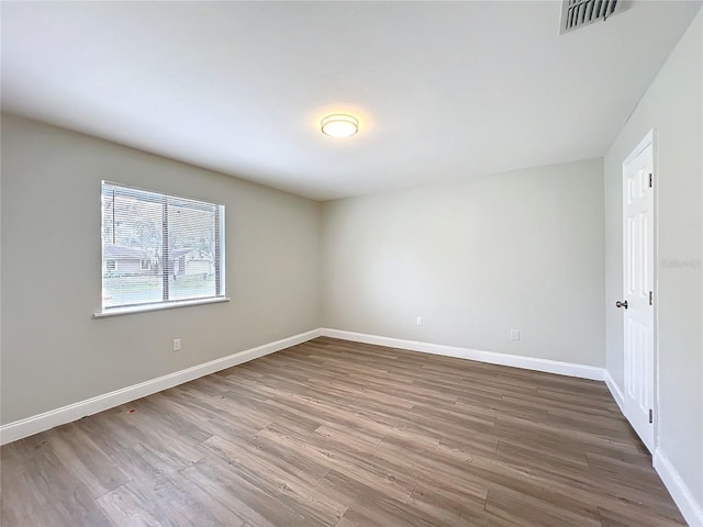 empty room featuring visible vents, baseboards, and wood finished floors