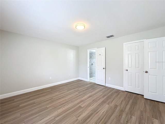 unfurnished bedroom featuring baseboards, visible vents, and wood finished floors