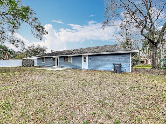 rear view of property featuring a yard, fence, and a patio