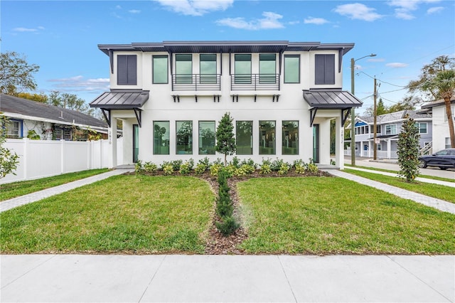 view of front of home featuring metal roof, a front lawn, a standing seam roof, and fence