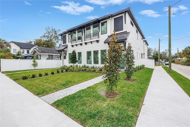 view of front facade featuring metal roof, fence, stucco siding, a standing seam roof, and a front yard