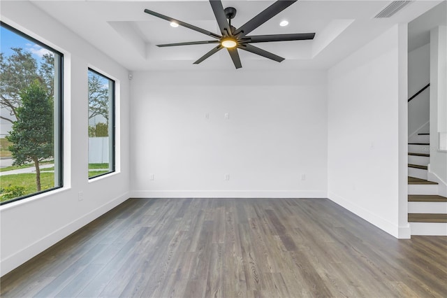 spare room with baseboards, visible vents, dark wood finished floors, stairs, and a tray ceiling