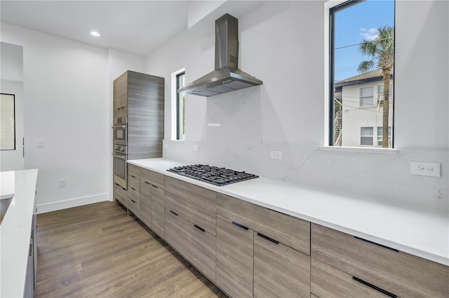 kitchen featuring light countertops, modern cabinets, a wealth of natural light, and range hood