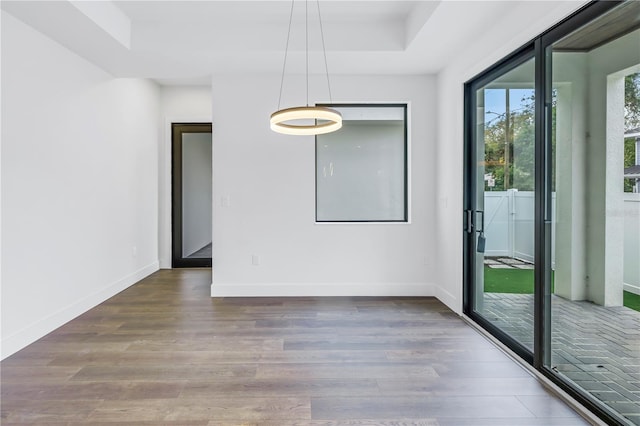 unfurnished room with dark wood-style flooring, a raised ceiling, and baseboards