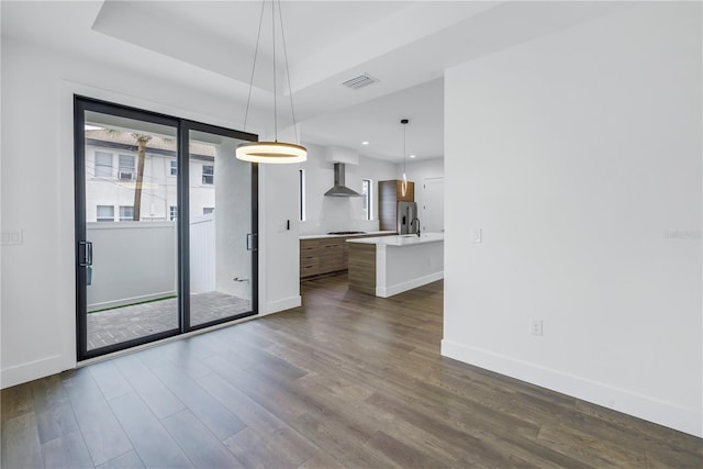 interior space with dark wood-style flooring, visible vents, a raised ceiling, and baseboards