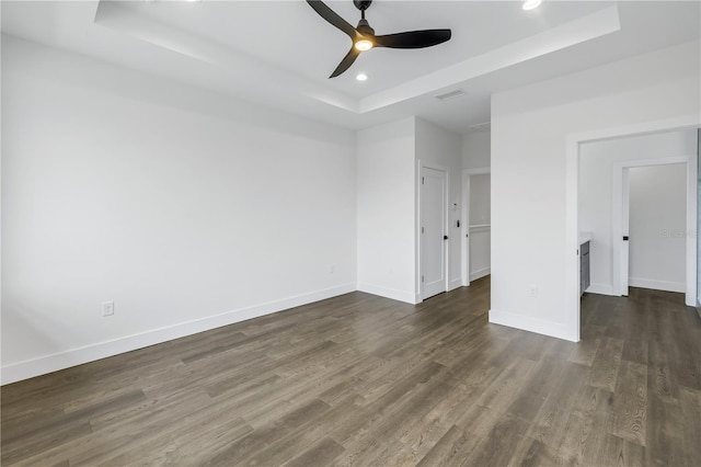 unfurnished room featuring a tray ceiling, recessed lighting, visible vents, dark wood-type flooring, and baseboards