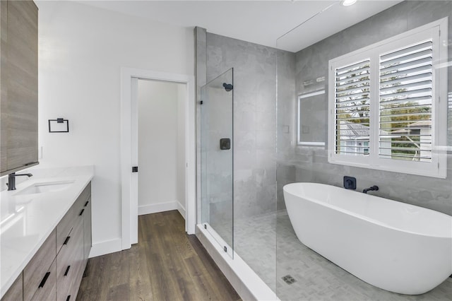 full bath featuring wood finished floors, a soaking tub, a shower stall, and vanity