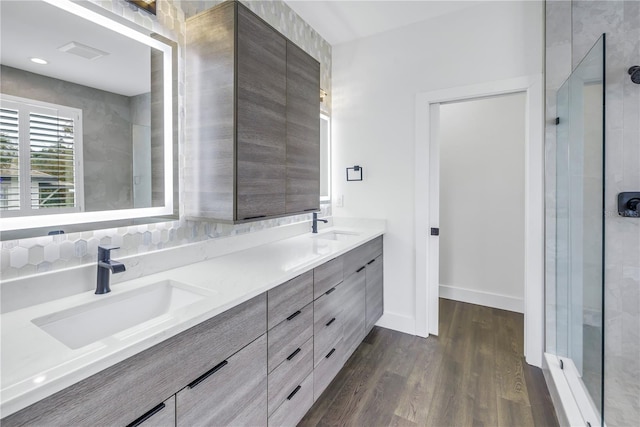 bathroom with wood finished floors, a sink, baseboards, and double vanity