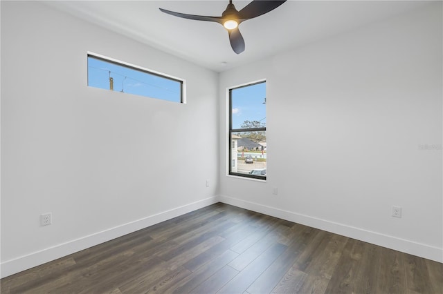 empty room featuring a ceiling fan, baseboards, and dark wood-type flooring