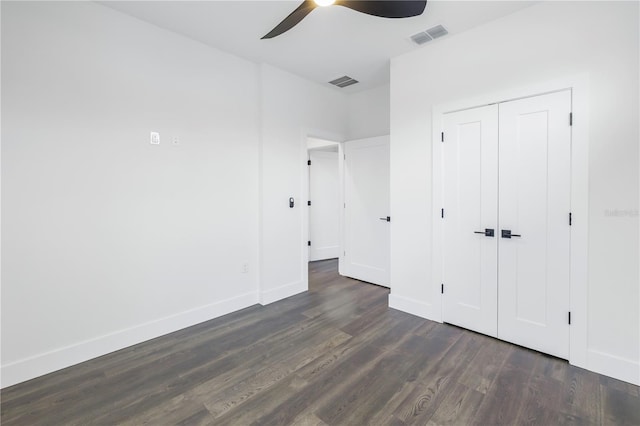 unfurnished bedroom with a closet, visible vents, dark wood finished floors, and baseboards