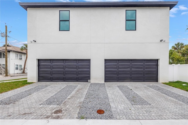 view of front of property featuring decorative driveway, an attached garage, and stucco siding