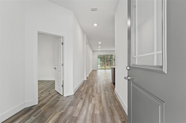 hall featuring light wood-style floors, visible vents, baseboards, and recessed lighting