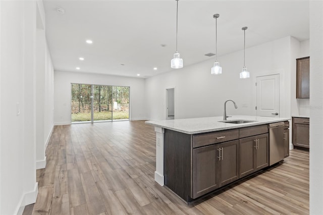 kitchen with a sink, open floor plan, dishwasher, and decorative light fixtures