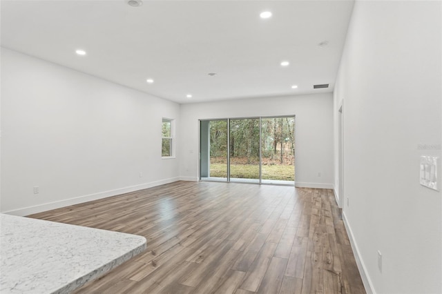 unfurnished living room featuring baseboards, wood finished floors, visible vents, and recessed lighting