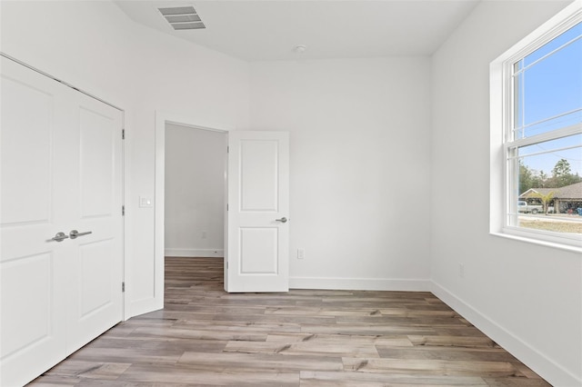 interior space featuring light wood-type flooring, visible vents, and baseboards