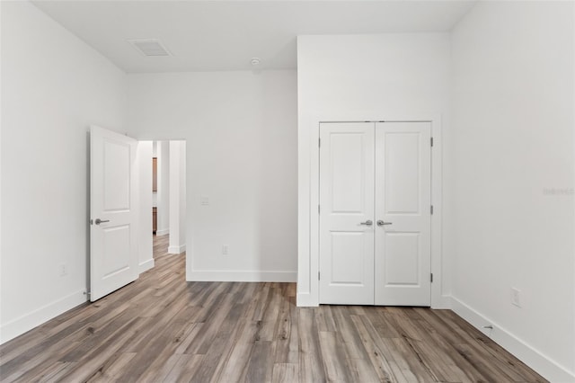 unfurnished bedroom with a closet, light wood-type flooring, and baseboards