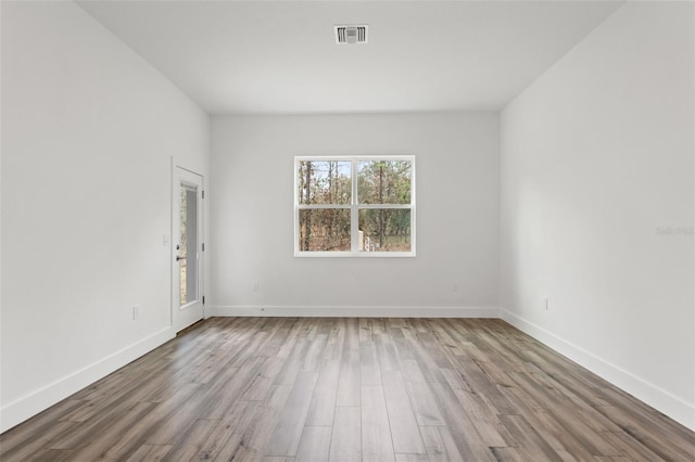 unfurnished room featuring light wood-type flooring, visible vents, and baseboards