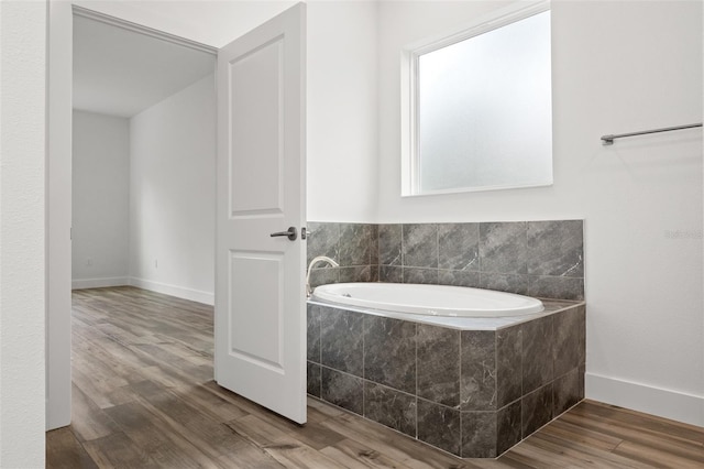 bathroom featuring a garden tub, wood finished floors, and baseboards