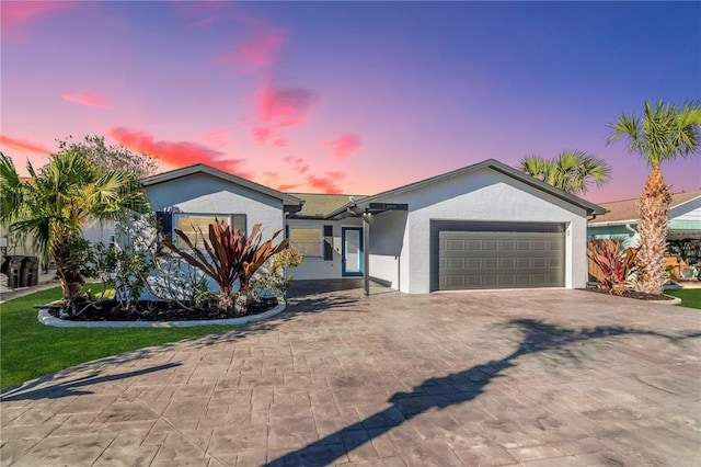 ranch-style home with decorative driveway, a garage, and stucco siding