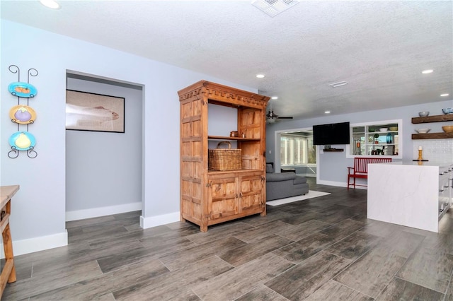 living room featuring visible vents, baseboards, a textured ceiling, and dark wood-style flooring