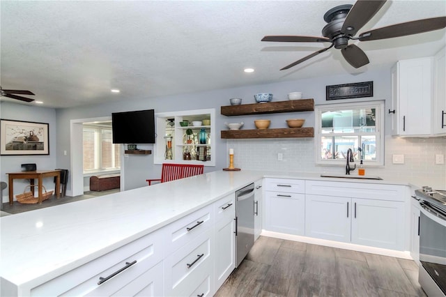 kitchen featuring open shelves, light countertops, appliances with stainless steel finishes, and a sink