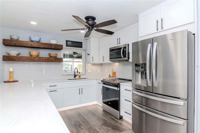 kitchen featuring a sink, open shelves, appliances with stainless steel finishes, and white cabinetry