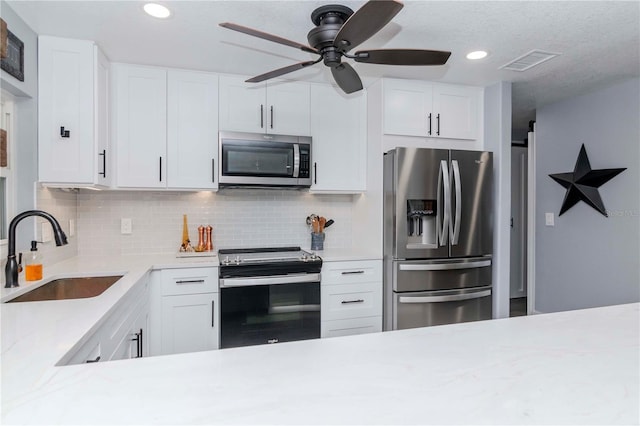 kitchen featuring visible vents, backsplash, light countertops, stainless steel appliances, and a sink