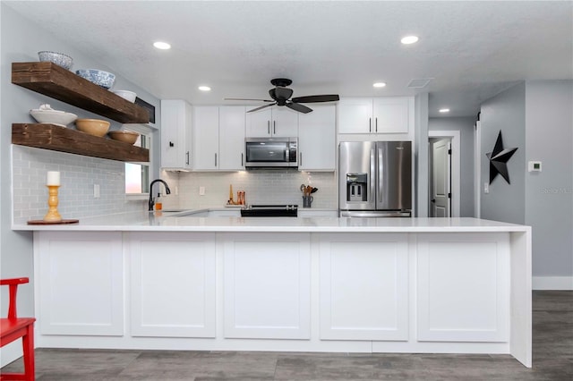 kitchen with open shelves, a peninsula, a sink, stainless steel appliances, and white cabinetry