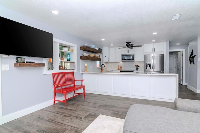 kitchen with open shelves, a peninsula, appliances with stainless steel finishes, white cabinets, and light countertops