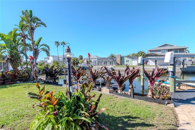 view of property's community featuring a yard, boat lift, and a boat dock