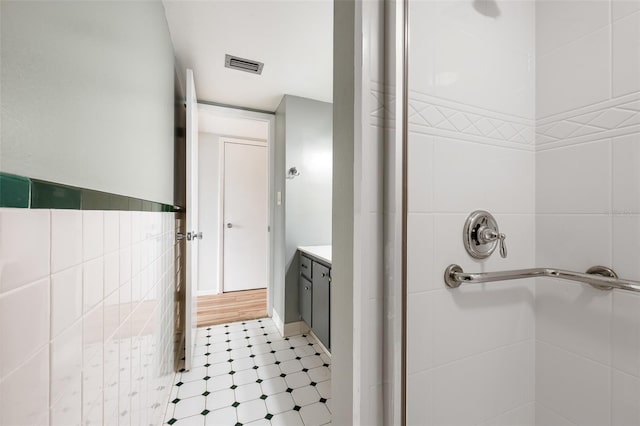 full bathroom with walk in shower, vanity, visible vents, and tile walls