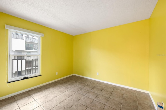 empty room with a textured ceiling, baseboards, and tile patterned floors