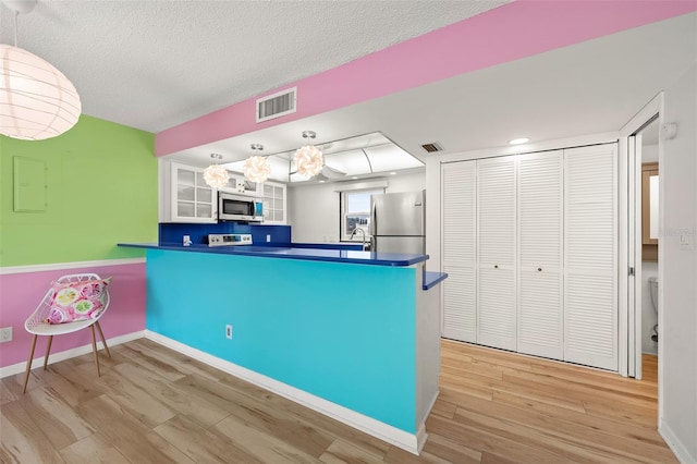 kitchen featuring hanging light fixtures, appliances with stainless steel finishes, dark countertops, and white cabinetry