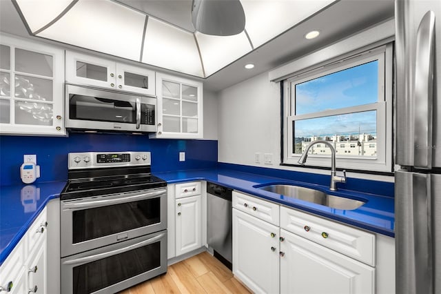 kitchen featuring dark countertops, white cabinets, stainless steel appliances, and a sink