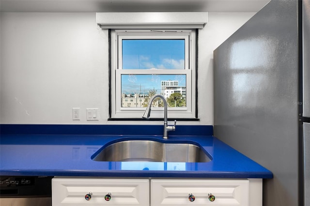 kitchen featuring dark countertops, white cabinets, a sink, and dishwashing machine