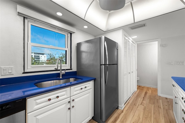 kitchen featuring visible vents, dark countertops, appliances with stainless steel finishes, white cabinetry, and a sink