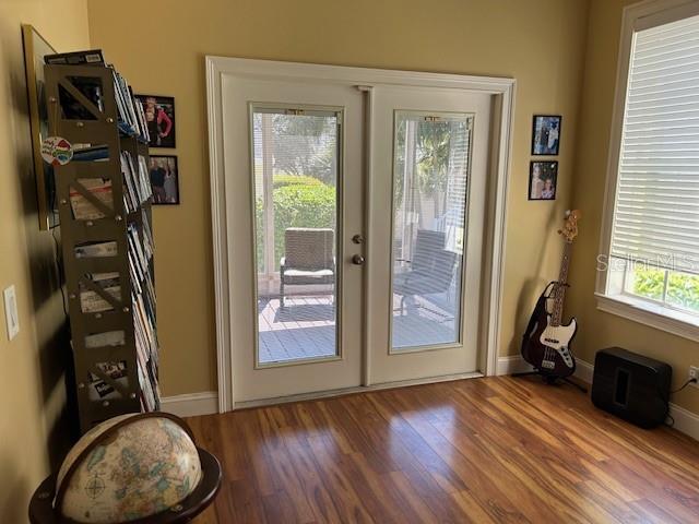 doorway with french doors, wood finished floors, and baseboards