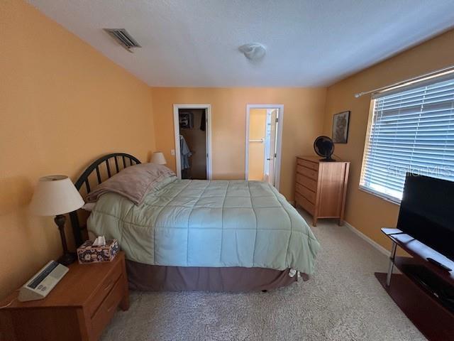 carpeted bedroom featuring a walk in closet, visible vents, and baseboards