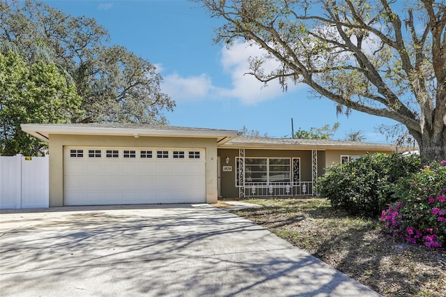 single story home with concrete driveway, fence, an attached garage, and stucco siding