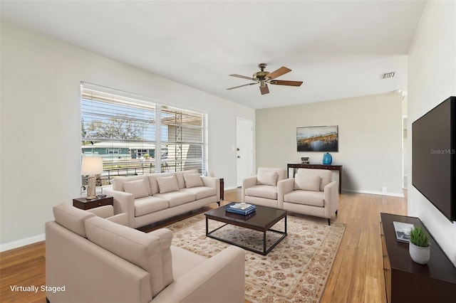 living area with a ceiling fan, baseboards, visible vents, and light wood finished floors