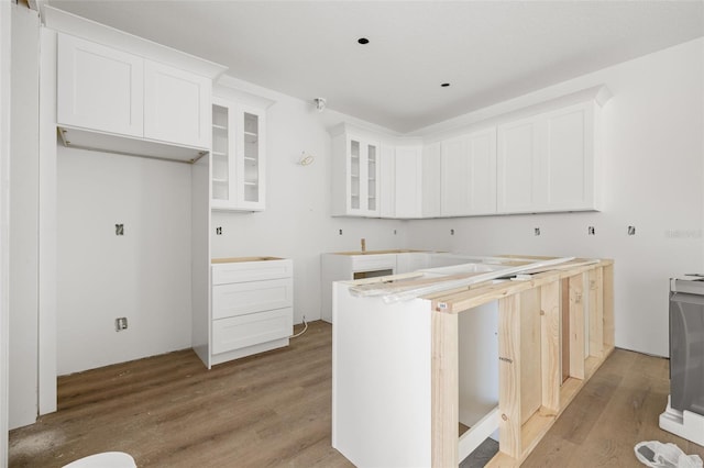 kitchen featuring wood finished floors, glass insert cabinets, and white cabinets