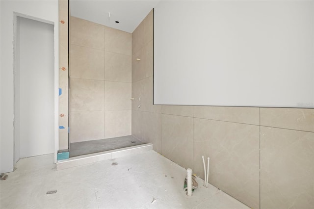 bathroom with tiled shower and tile walls