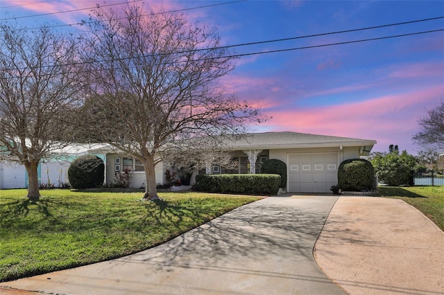 ranch-style home featuring an attached garage, concrete driveway, a front yard, and stucco siding